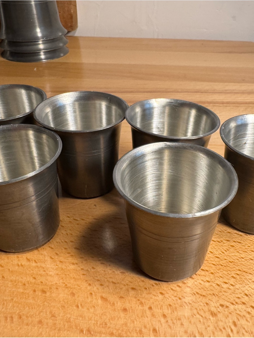 A set of six antique hand-crafted pewter shot glasses.